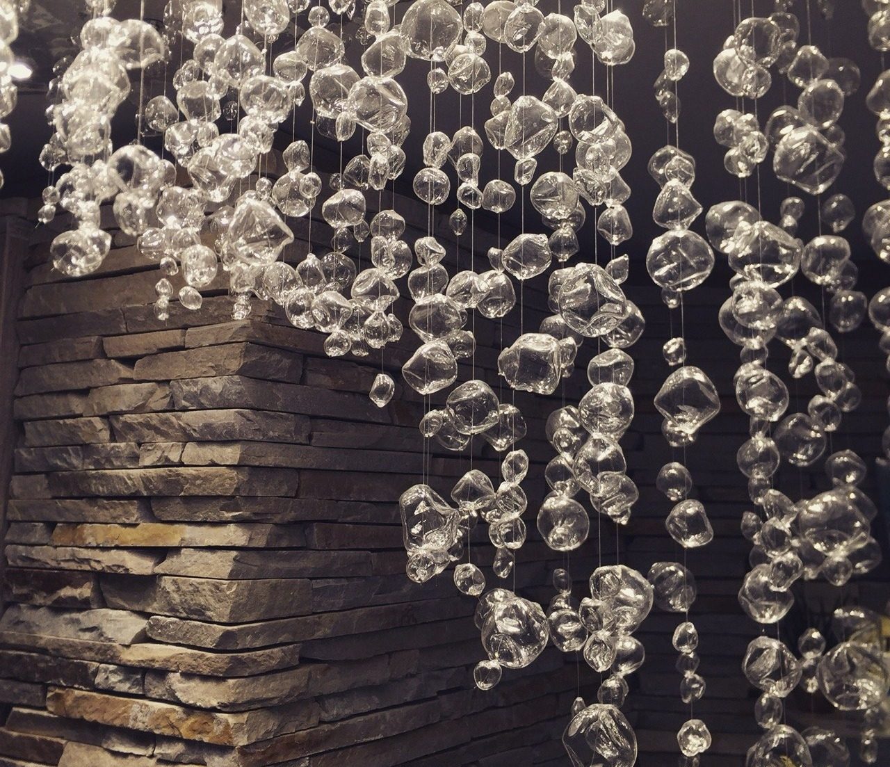 Hängende Glaskugeln vor einer Natursteinwand